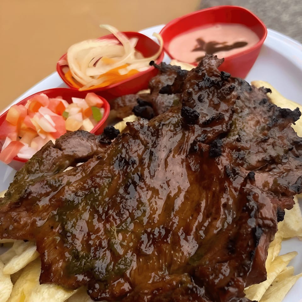 Grilled Mexican steak with fries, a side of pico de gallo, pickled onions, and pink sauce.